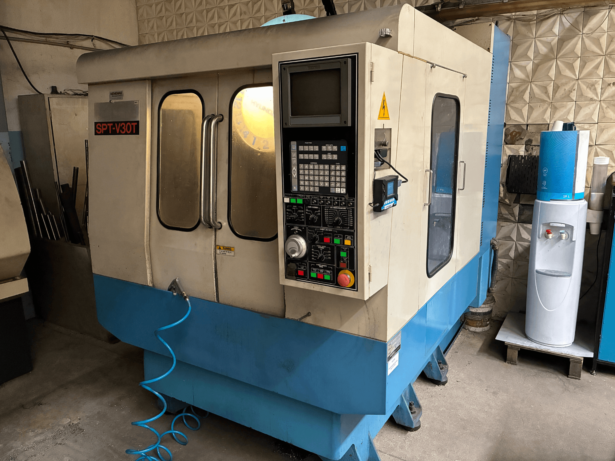 SPT-V30T Fräsmaschine in der Vorderansicht mit einem Bedienfeld mit Tasten und einem blauen Sockel, in einer Werkstatt.